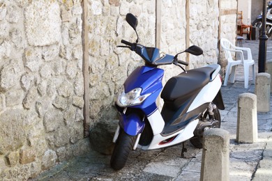 Beautiful scooter parked near stone wall outdoors