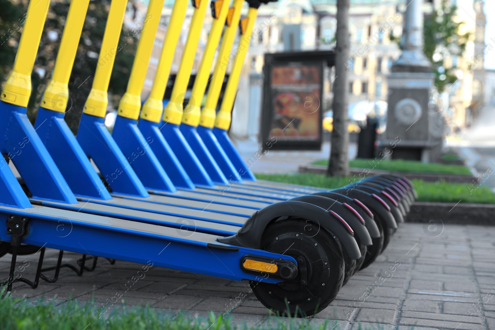 Photo of Many modern electric scooters parked on city street, closeup. Rental service