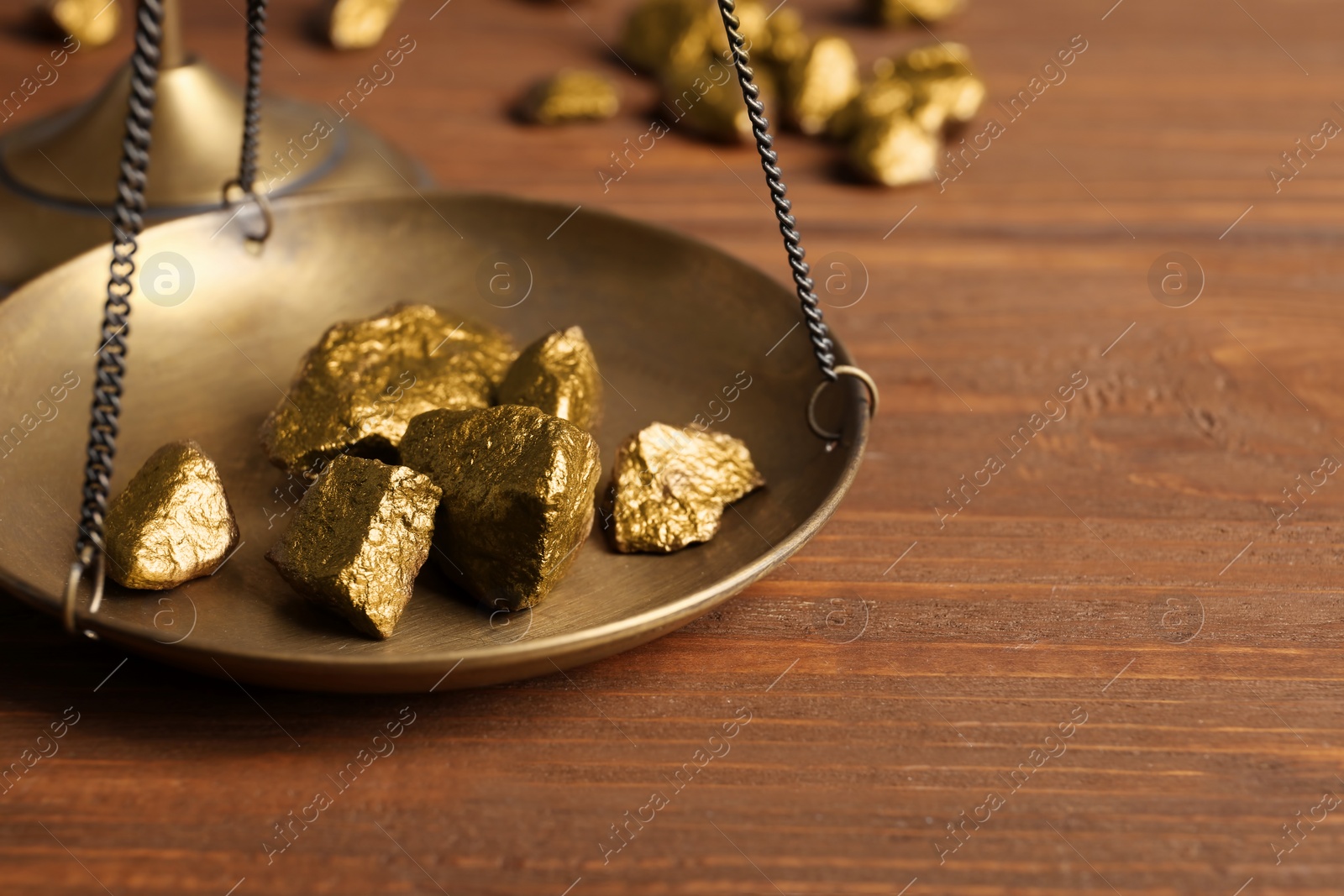 Photo of Scale pan with gold lumps on wooden table, closeup. Space for text