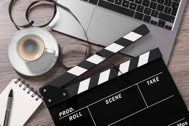 Photo of Flat lay composition with movie clapper and film reel on wooden table