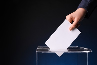 Photo of Woman putting her vote into ballot box on dark blue background, closeup. Space for text