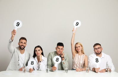 Photo of Panel of judges holding different score signs at table on beige background