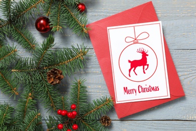 Image of Greeting card with text Merry Christmas on grey wooden table, flat lay