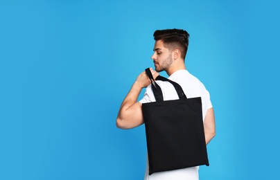 Portrait of young man with eco bag on blue background. Space for text