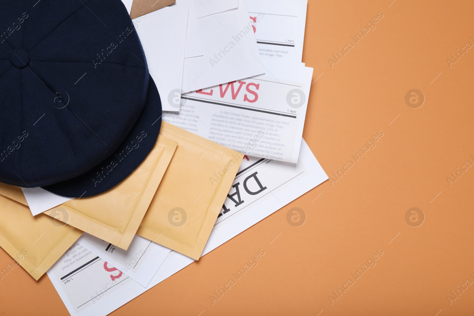 Photo of Postman hat, newspapers and mails on light brown background, flat lay. Space for text