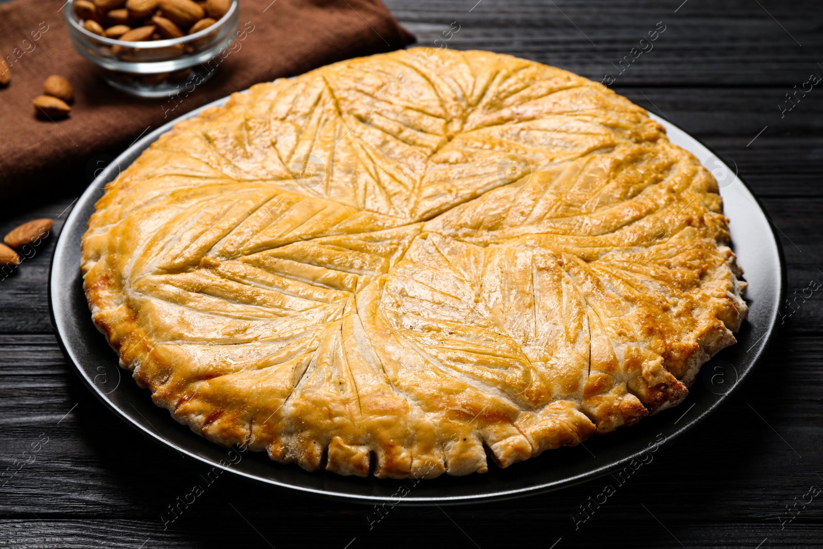 Photo of Traditional galette des rois on black wooden table, closeup