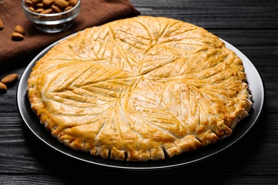 Photo of Traditional galette des rois on black wooden table, closeup