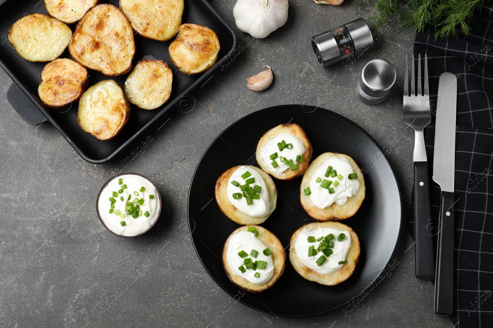 Photo of Delicious potato wedges with sour cream dressing on grey table, flat lay