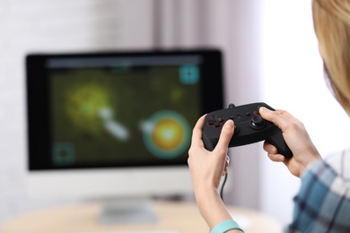 Photo of Young woman playing video game at home, closeup