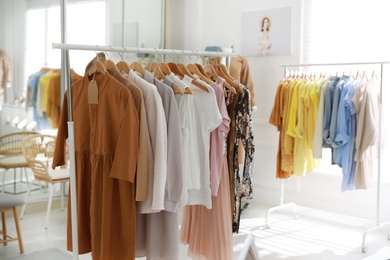 Photo of Stylish women's clothes on rack in modern boutique