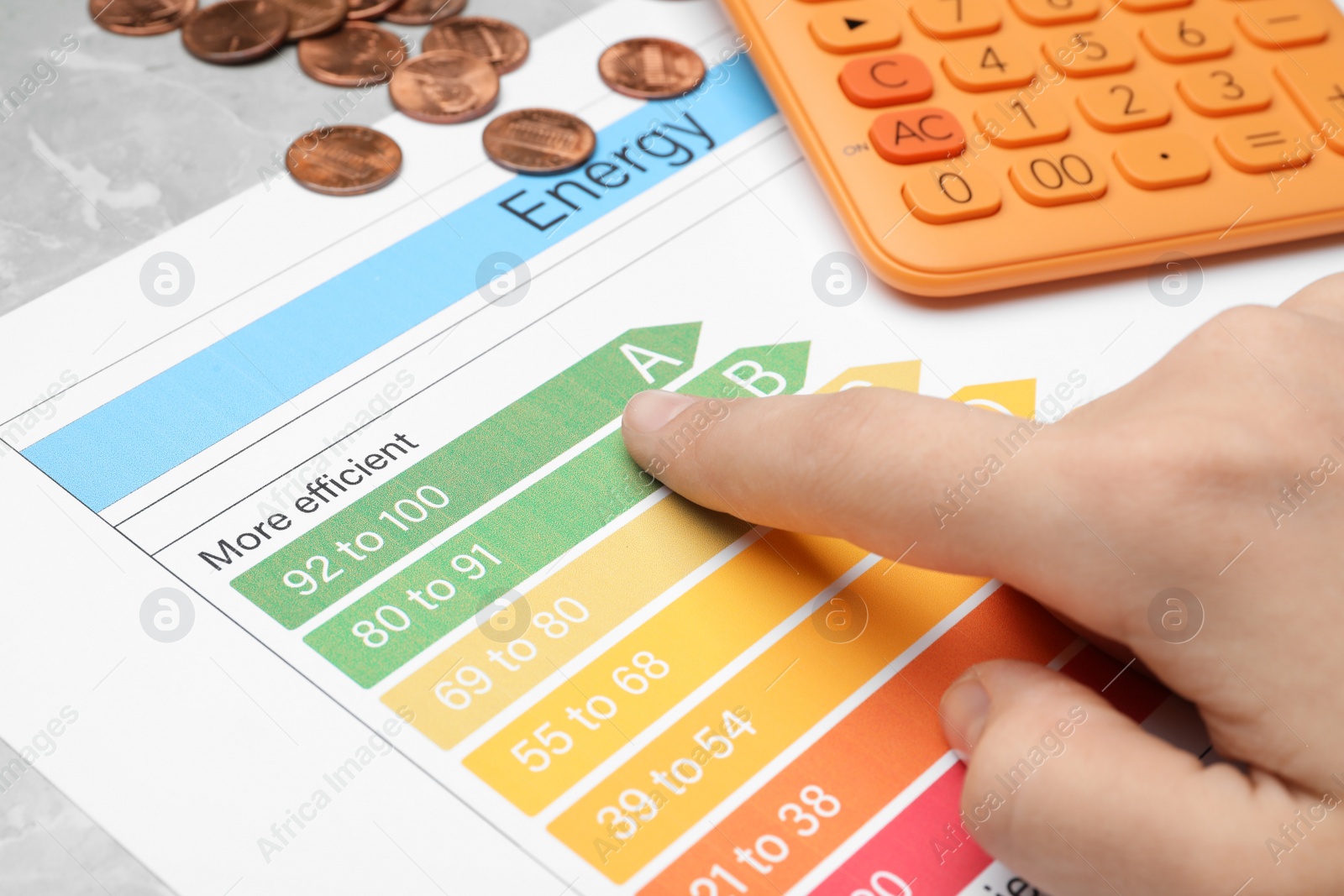 Photo of Woman with energy efficiency rating chart at table, closeup