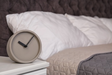Photo of Stylish alarm clock on nightstand in bedroom. Space for text