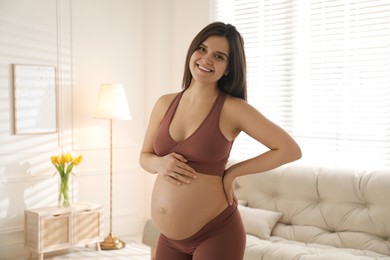 Pregnant young woman touching belly at home