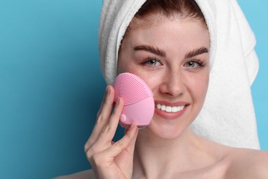 Photo of Washing face. Young woman with cleansing brush on light blue background, closeup. Space for text