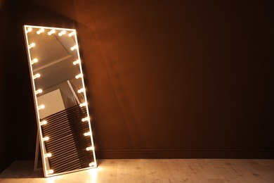 Photo of Stylish mirror with light bulbs near brown wall indoors, space for text. Interior element