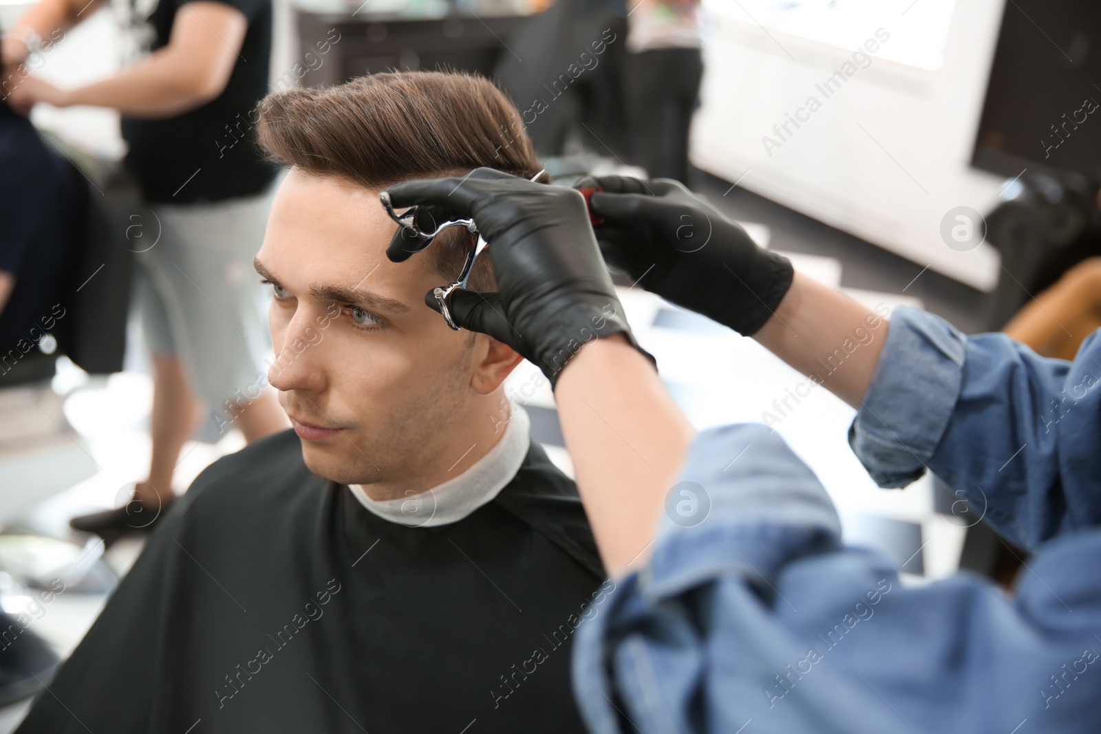 Photo of Professional barber working with client in hairdressing salon. Hipster fashion