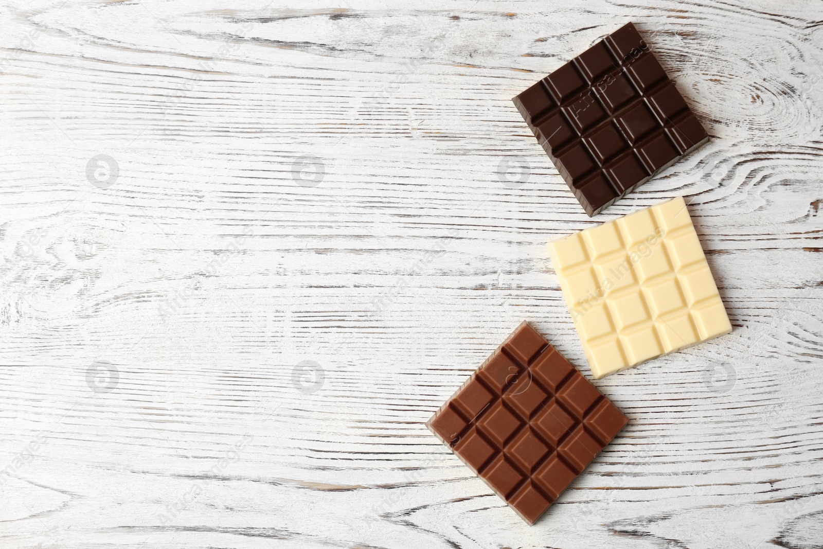 Photo of Different chocolate bars on wooden background, top view