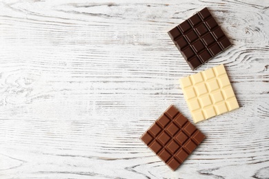 Photo of Different chocolate bars on wooden background, top view