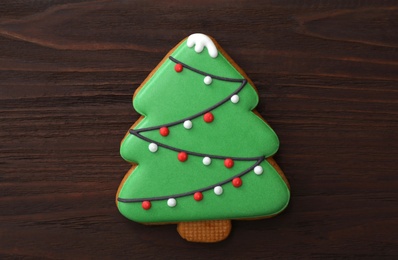 Photo of Christmas tree shaped cookie on wooden table, top view