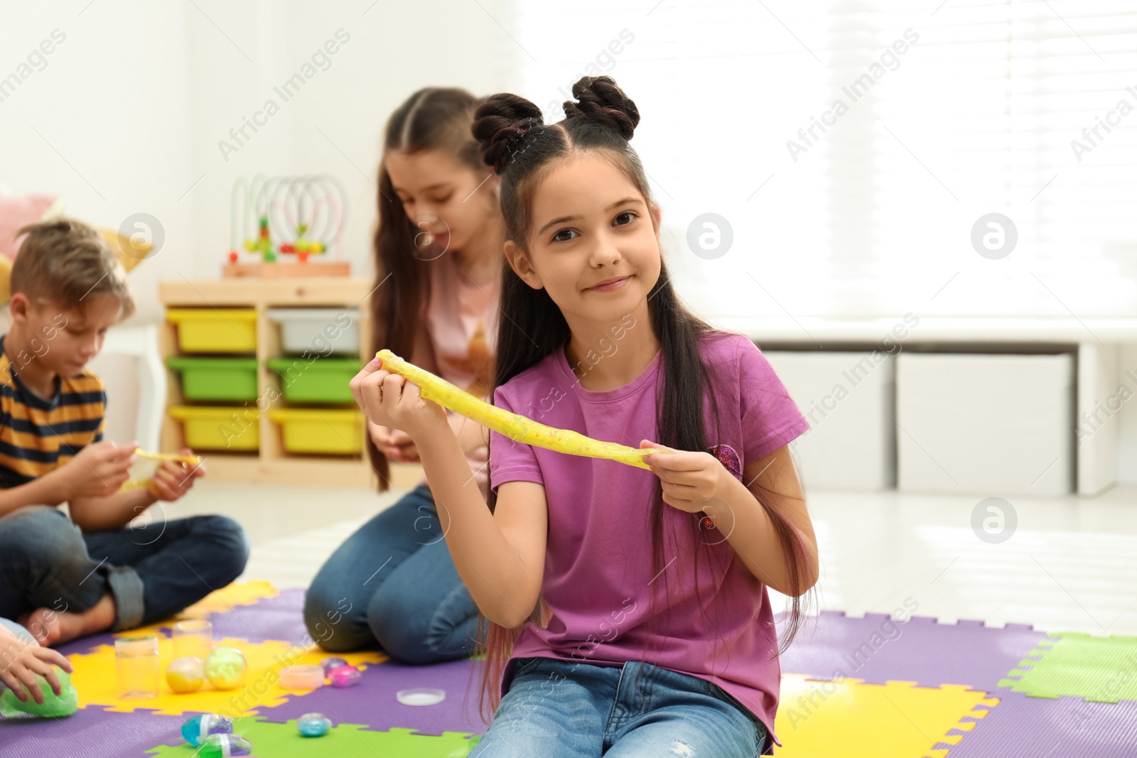 Photo of Happy little girl playing with slime in room