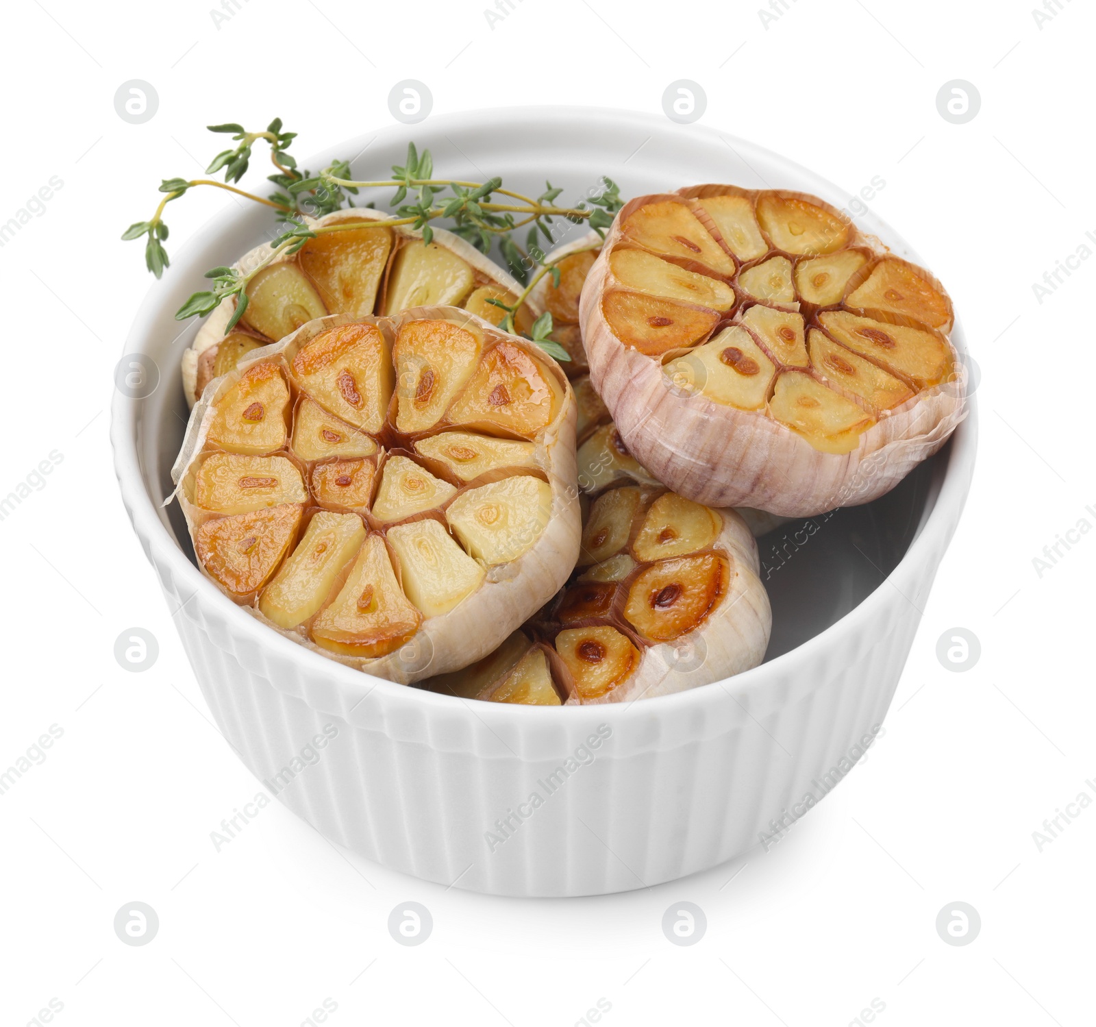 Photo of Heads of fried garlic and thyme in bowl isolated on white