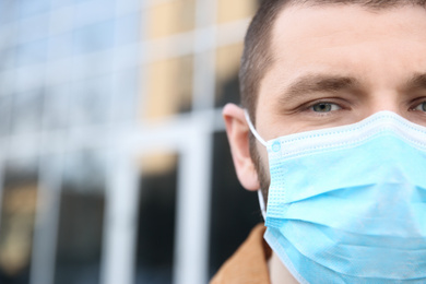 Man wearing disposable mask outdoors, closeup. Dangerous virus