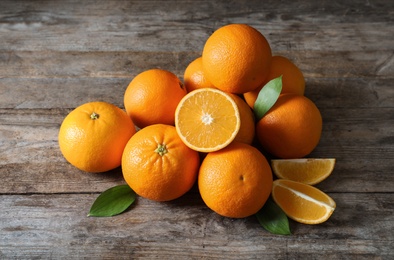 Photo of Fresh oranges with leaves on wooden background