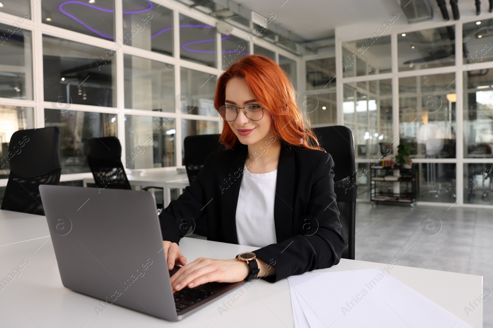 Photo of Woman working with laptop at white desk in office