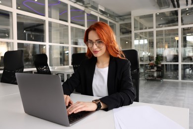 Photo of Woman working with laptop at white desk in office