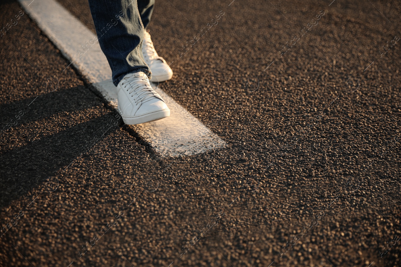 Photo of Man walking along white line on road, closeup with space for text. Way concept