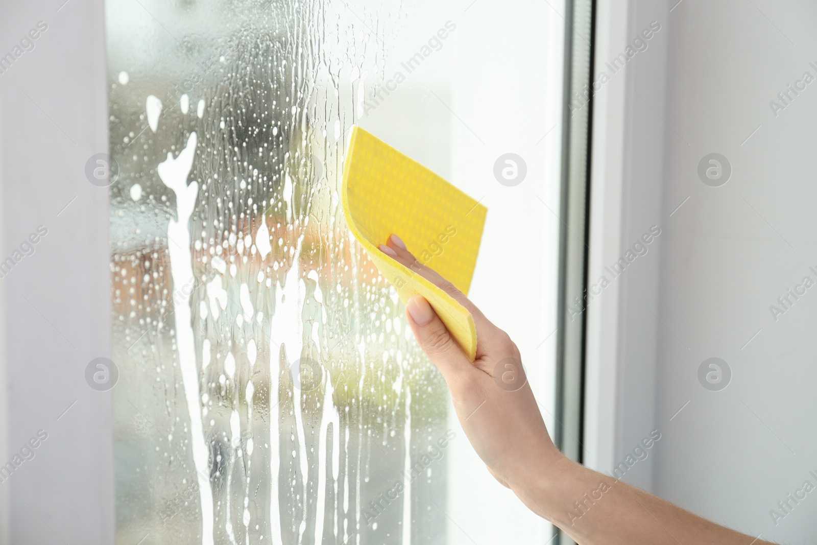 Photo of Woman cleaning window with rag indoors, closeup