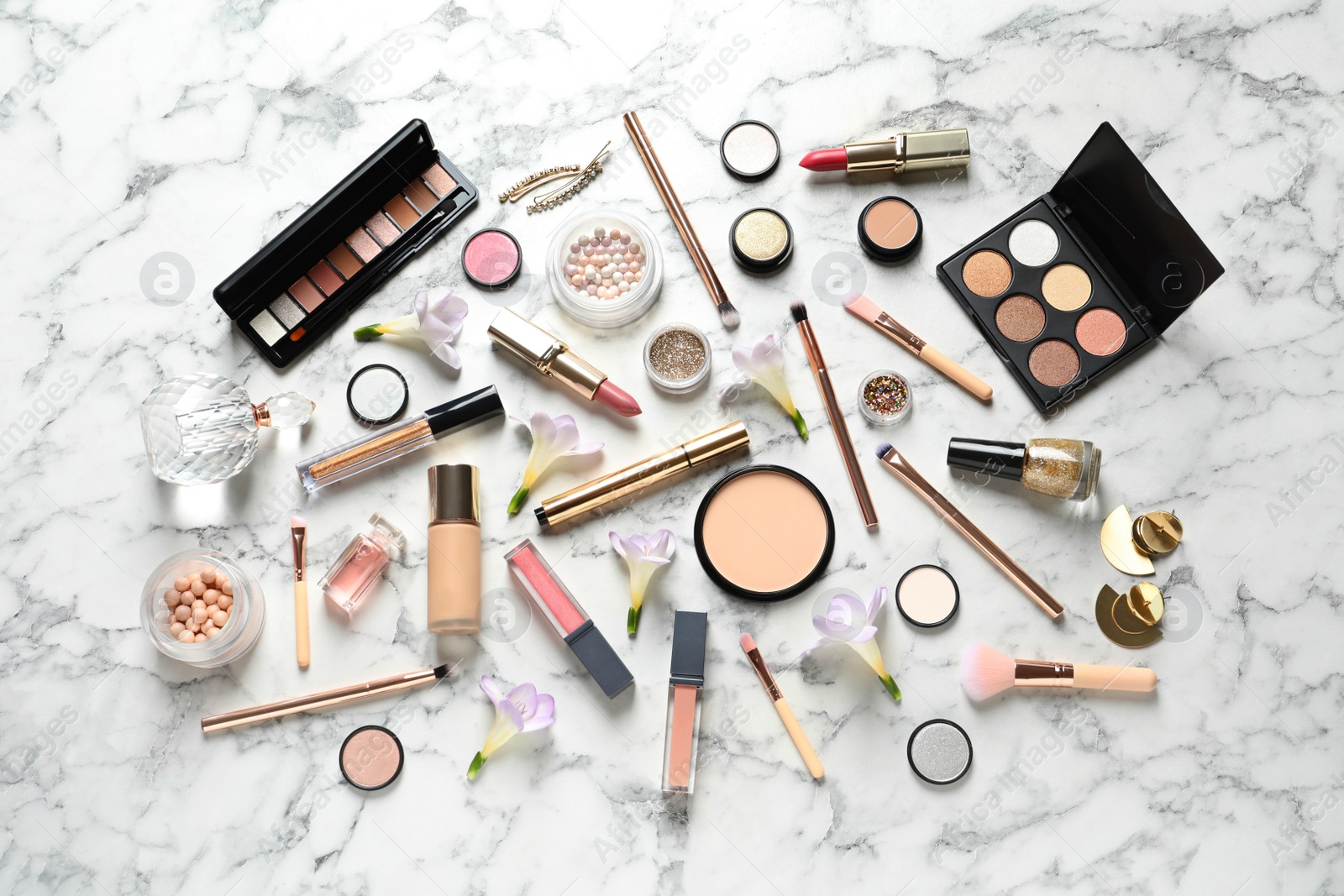 Photo of Many different makeup products and spring flowers on marble background, flat lay