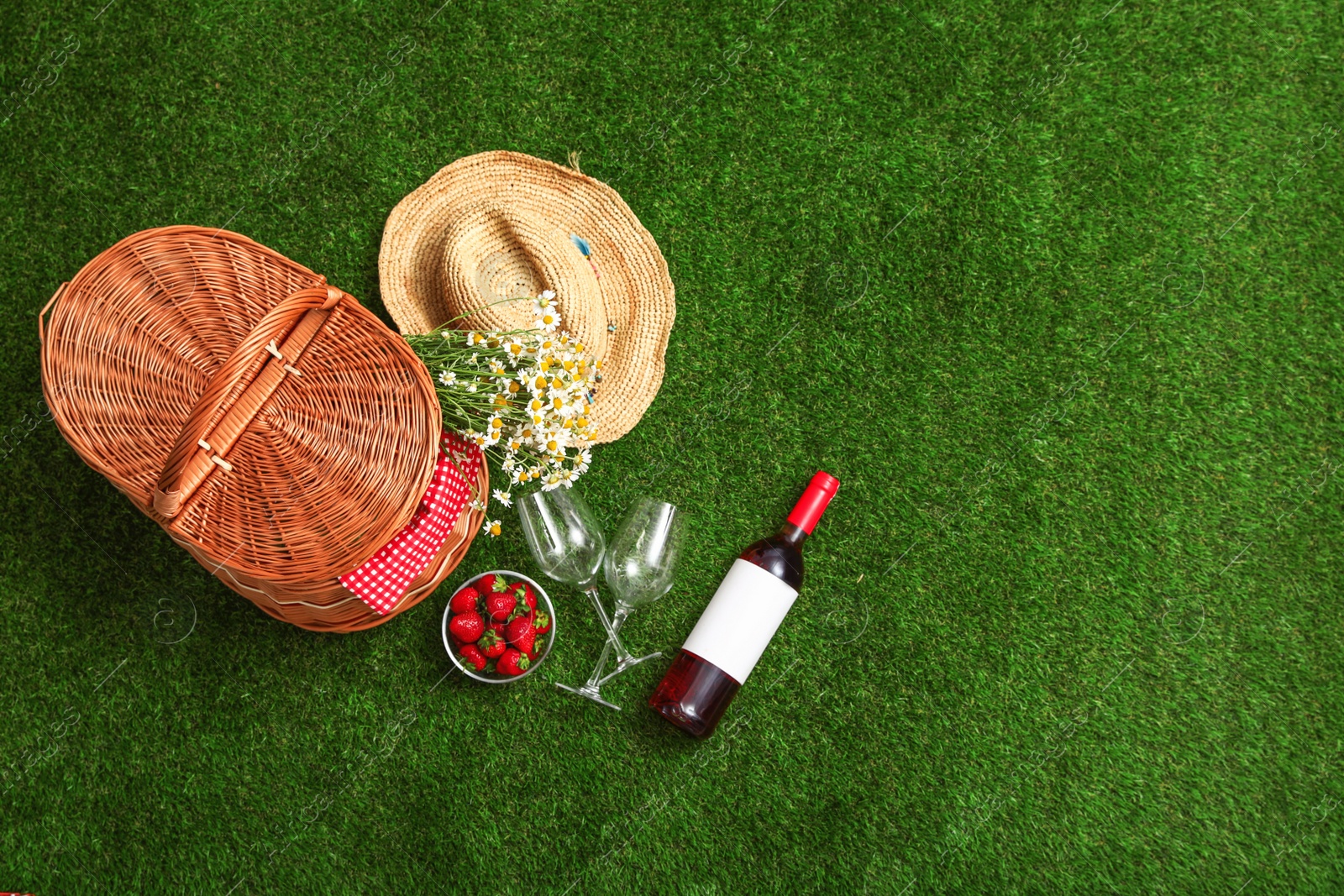 Photo of Flat lay composition with picnic basket, wine and strawberries on grass, space for text