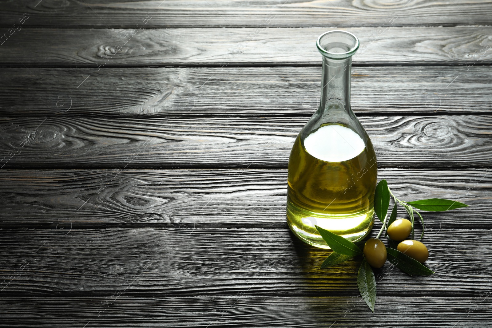 Photo of Bottle with fresh olive oil on wooden table