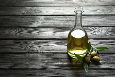 Photo of Bottle with fresh olive oil on wooden table