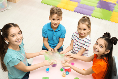 Photo of Happy children playing with slime at table indoors, above view