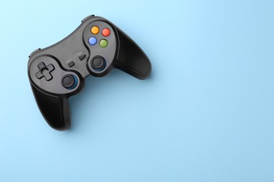 Photo of Wireless game controller on light blue background, top view. Space for text