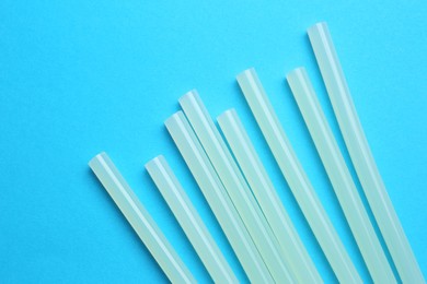 Many glue sticks on light blue background, flat lay