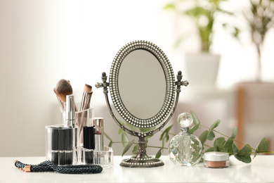 Photo of Mirror and makeup products on white table indoors