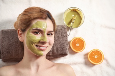 Beautiful woman with mask on face relaxing in spa salon, top view