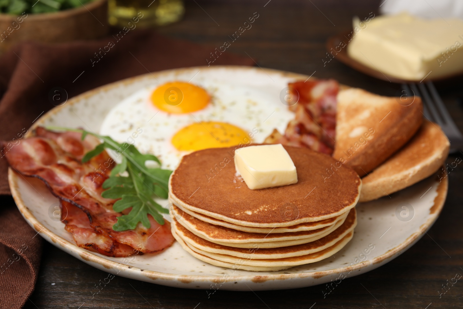 Photo of Tasty pancakes served with fried eggs and bacon on wooden table, closeup