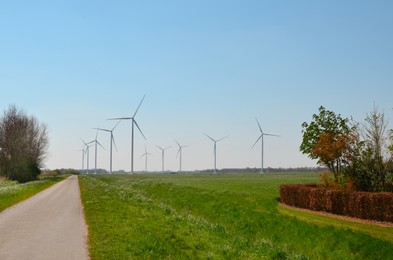Photo of Beautiful view of countryside with road and wind turbines on sunny day. Alternative energy source