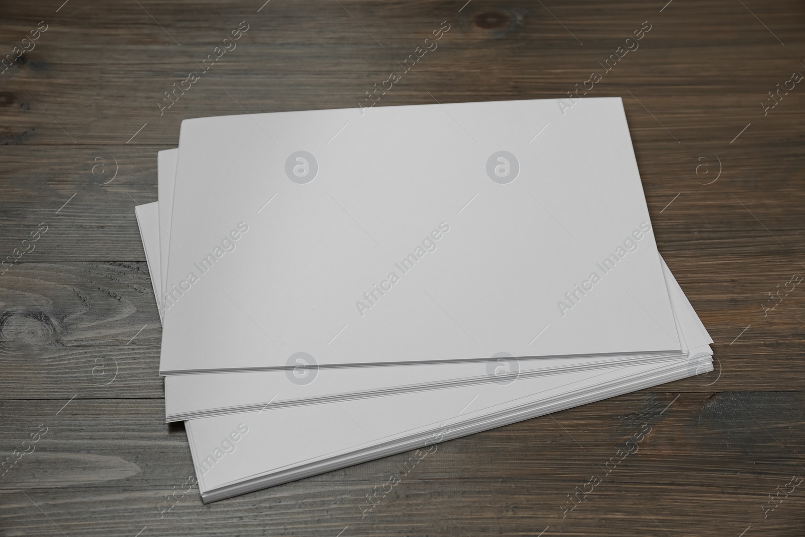 Photo of Stack of blank paper sheets on wooden table. Brochure design