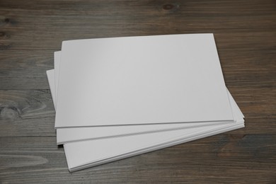 Photo of Stack of blank paper sheets on wooden table. Brochure design