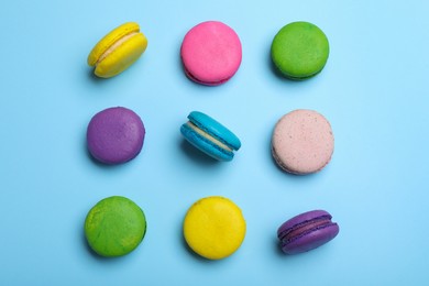 Delicious colorful macarons on light blue background, flat lay