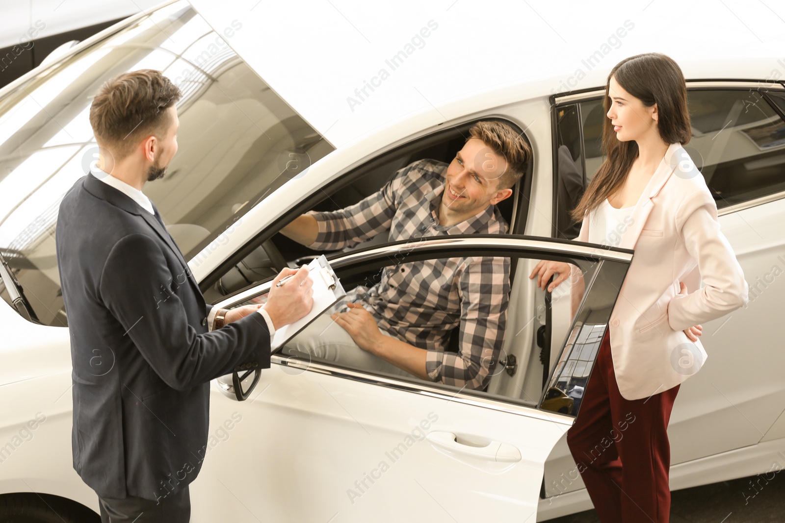 Photo of Young couple buying new car in salon