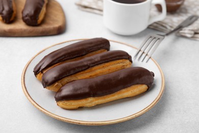 Photo of Delicious eclairs covered with chocolate on grey table