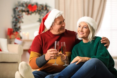 Happy mature couple with glasses of champagne at home. Christmas celebration