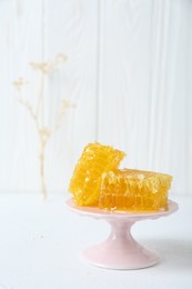 Photo of Stand with natural honeycombs on white table. Space for text
