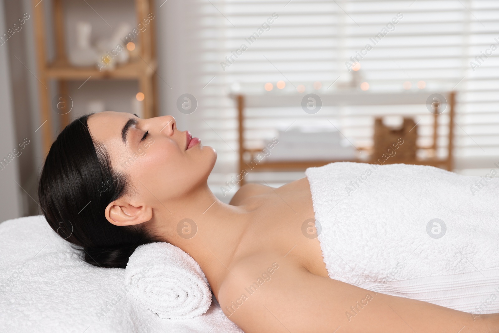 Photo of Beautiful woman relaxing on massage table in spa salon